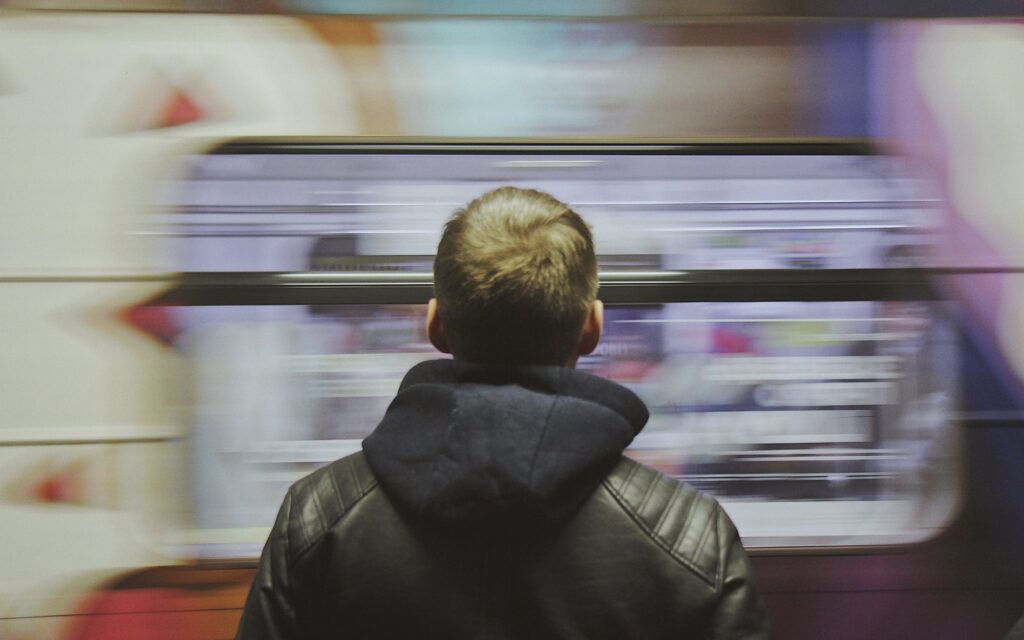 Man standing on a platform as a train blurs past, the details moving too fast to see