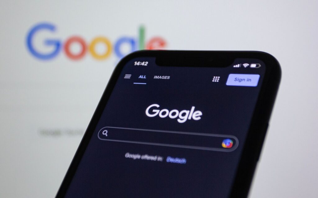 Smartphone showing the Google search page in front of a large Google logo
