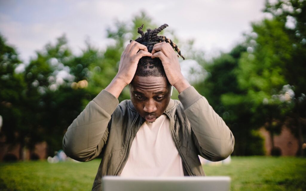 Stressed business owner clutching his head while looking at disappointing results on his laptop