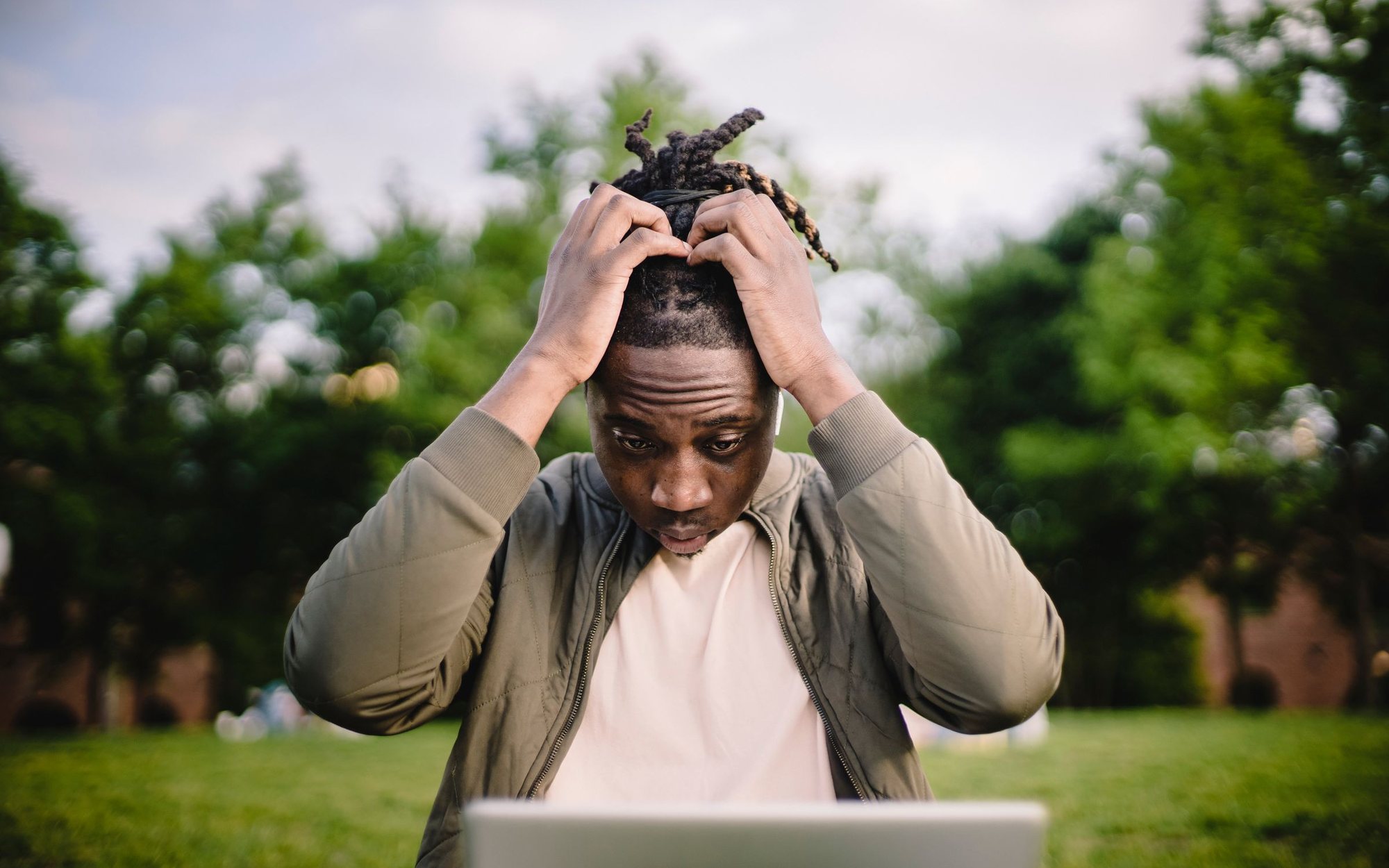 Stressed business owner clutching his head while looking at disappointing results on his laptop